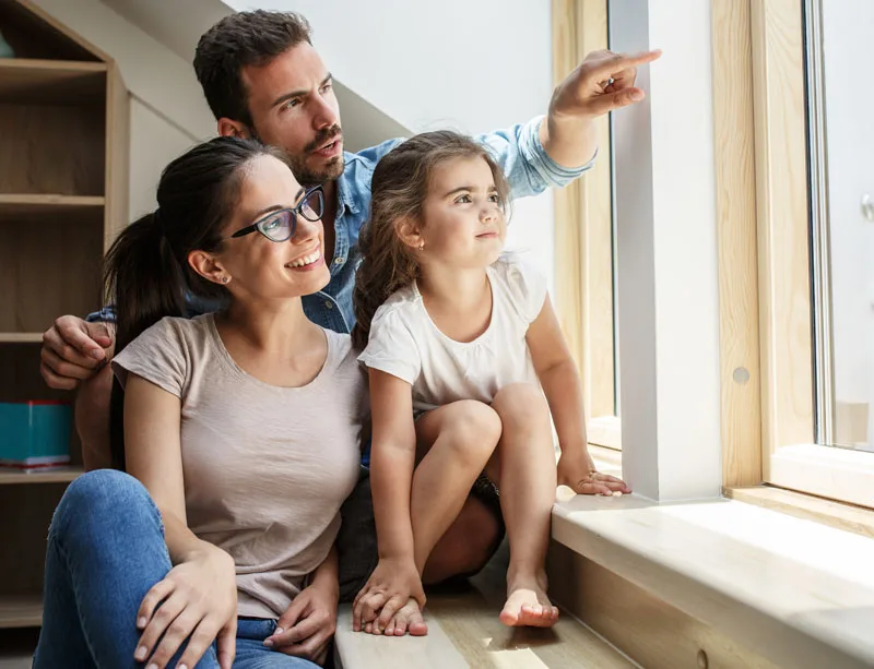 presto_family_window Happy family smiling and enjoying the view through their home’s impact windows and doors